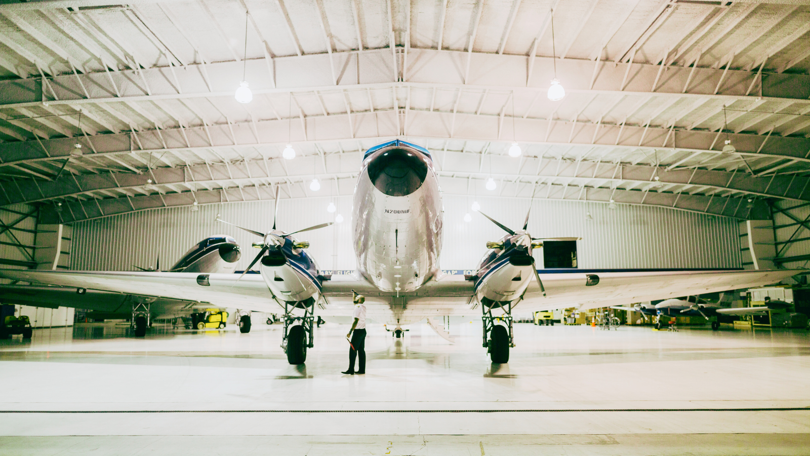 Professional holding AASSC certificate in a modern hangar.